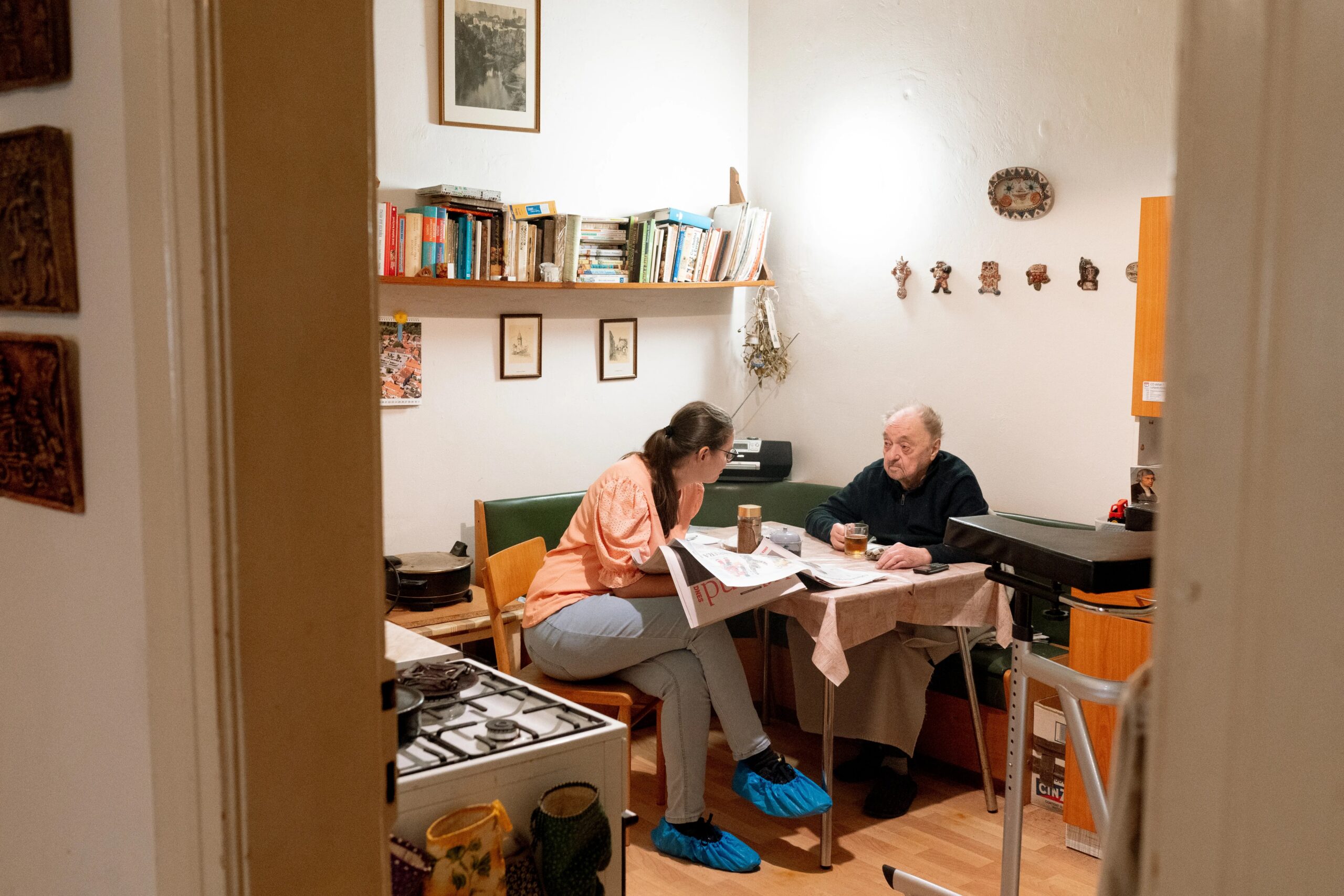 benefits of professional dog training classes - Warm scene of a caregiver and senior having a friendly conversation over coffee in Prague.