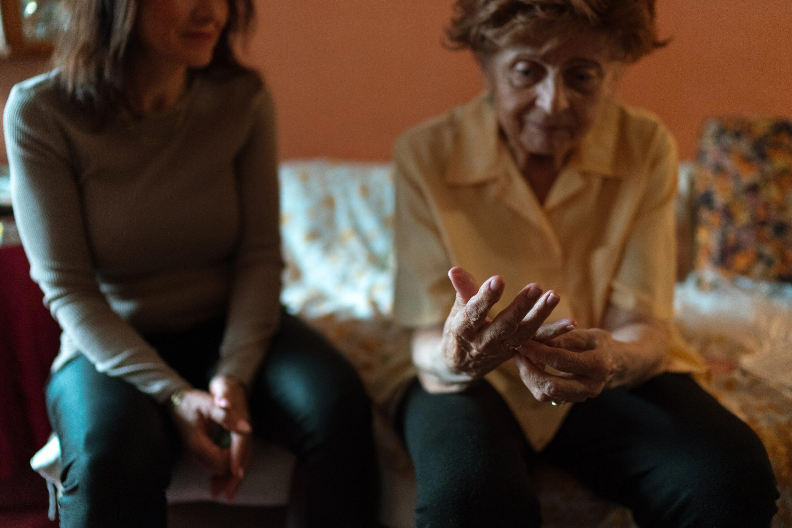 benefits of professional dog training classes - An elderly woman and her caregiver share a moment on the couch, embodying companionship.