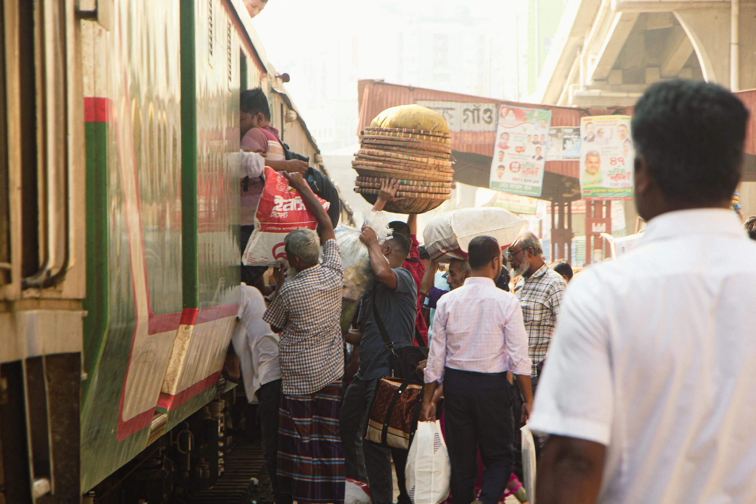long-term dog boarding for frequent travelers - Passengers boarding a train amid bustling activity at a railway station in Dhaka, Bangladesh.