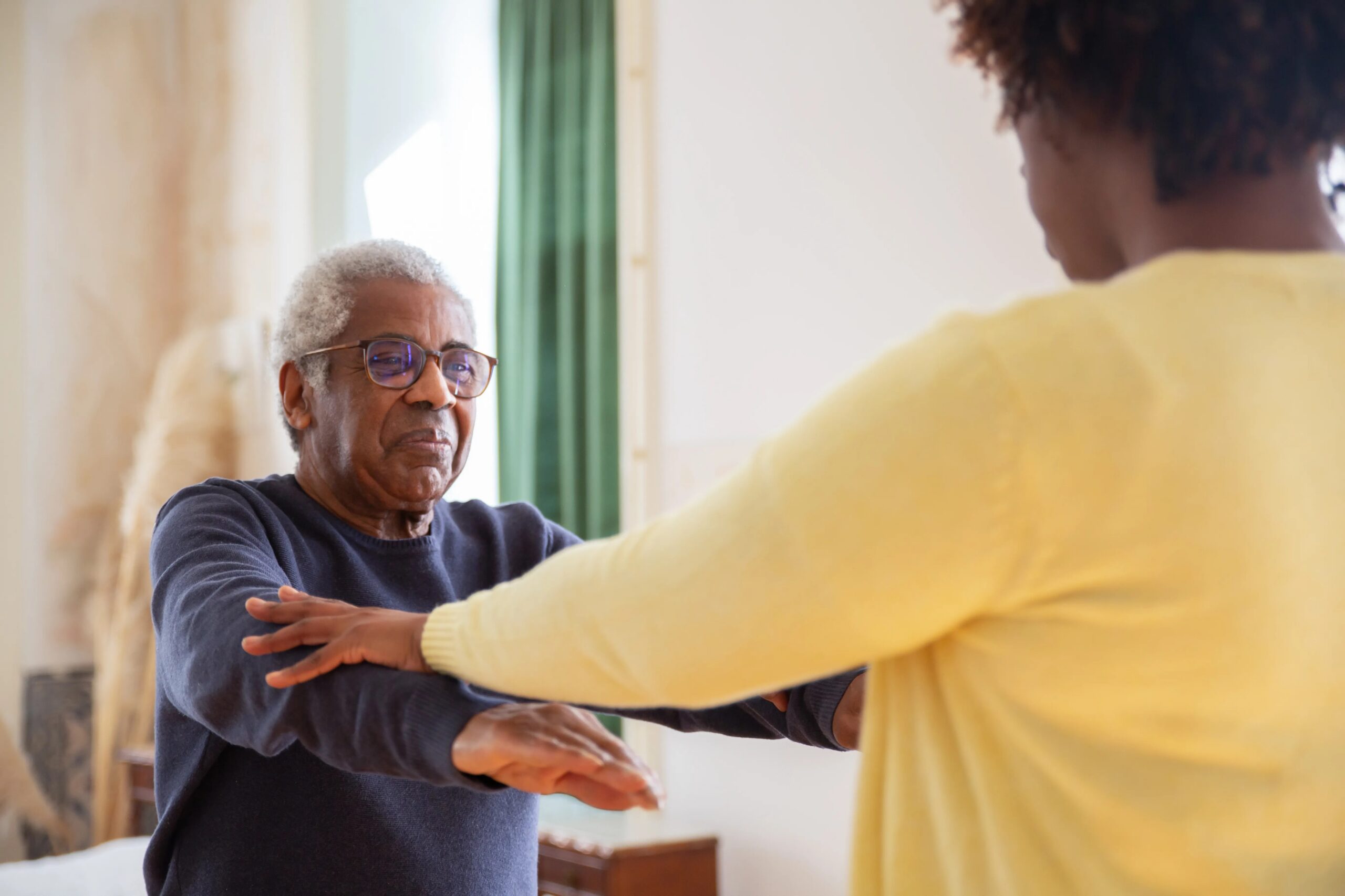basic dog training commands every dog should know - An elderly man with a caregiver assisting him in exercise at home.
