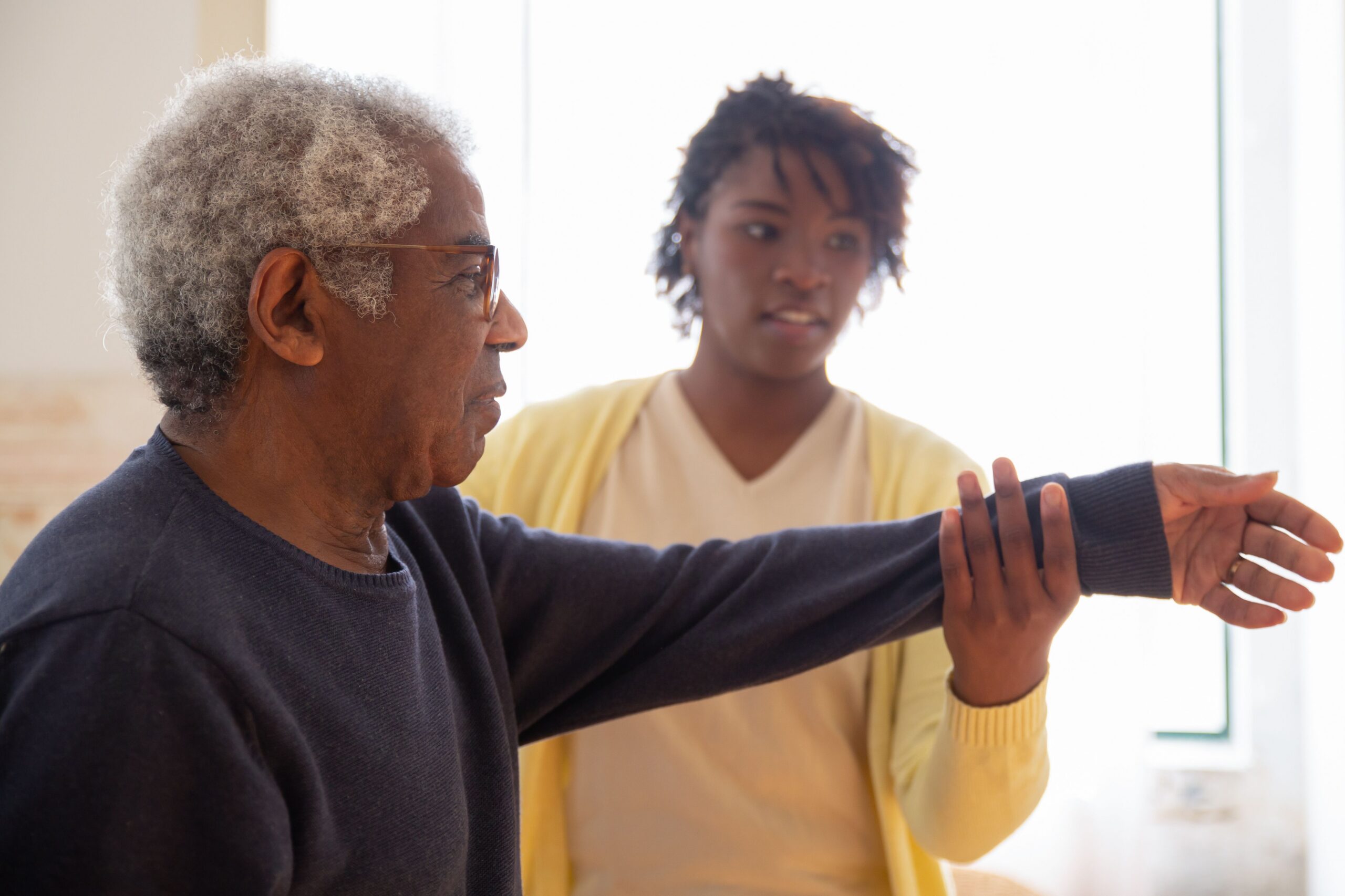 basic dog training commands every dog should know - A caregiver helps an elderly man with arm exercises in a warm and caring environment.